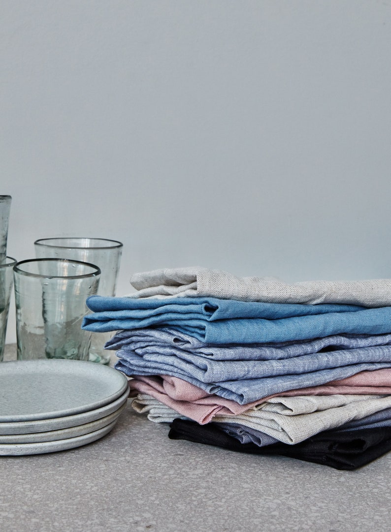 a pile of kitchen linens next to glasses and plates