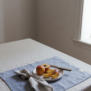 an angled view of a table with a placemat, napkin, nectarines on a plate