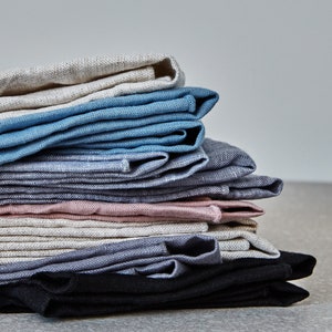 a stack of natural coloured kitchen linens on a grey surface