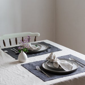 a set of two placemats on a table with napkins and flowers