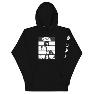 May include: Black hoodie with a white graphic of a woman's face in five different sections. The graphic is on the front of the hoodie. The left sleeve has a white graphic of a crescent moon, a full moon, and a sun.