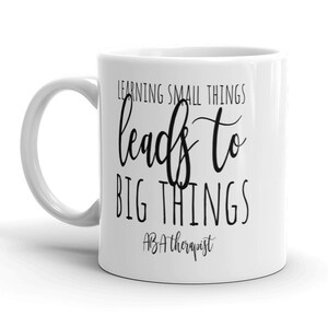 May include: White ceramic coffee mug with black text that reads "Learning small things leads to big things ABA therapist".