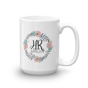 May include: White ceramic mug with a floral wreath design and the text "HR Gangsta" in black lettering.