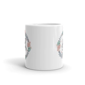May include: White ceramic mug with a floral wreath design and the text "Don't worry, be happy" in black lettering.