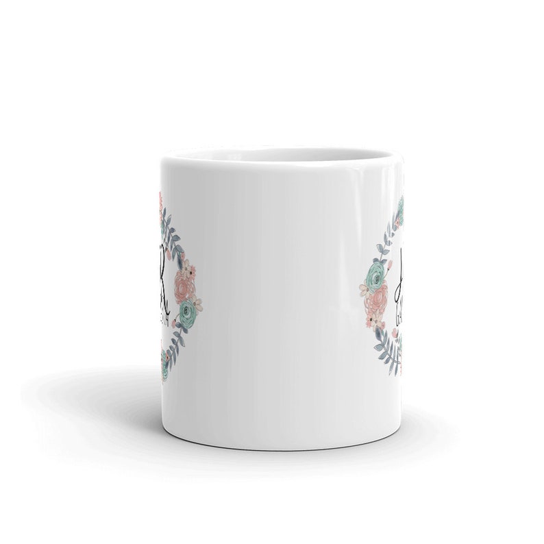 May include: White ceramic mug with a floral wreath design and the text "Don't worry, be happy" in black lettering.
