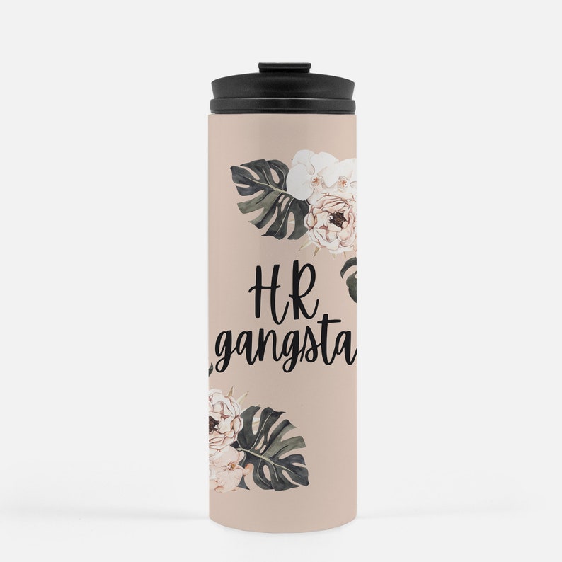 May include: A beige travel mug with a black lid, featuring the text "HR gangsta" in black script. The mug is decorated with floral and leaf illustrations in white, pink, and green.