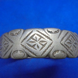 May include: A silver bracelet with a geometric design. The bracelet is made of metal and has a smooth finish.