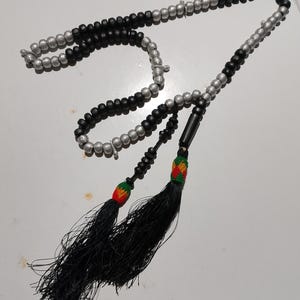May include: A black and silver prayer beads with black tassels and red, green, and yellow accents.