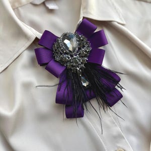 Purple brooch with feather.