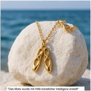 Könnte beinhalten: Eine goldfarbene Halskette mit einem Anhänger in Form eines Paares Ballettschuhe mit überkreuzten Riemen. Der Anhänger hängt an einer feinen goldfarbenen Kette mit Karabinerverschluss. Der Text unten lautet: Das Motiv wurde mit Hilfe künstlicher Intelligenz erstellt.