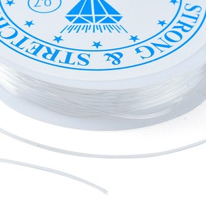 May include: A spool of clear elastic string with a white label that says "Strong & Stretch" and has a blue diamond logo.