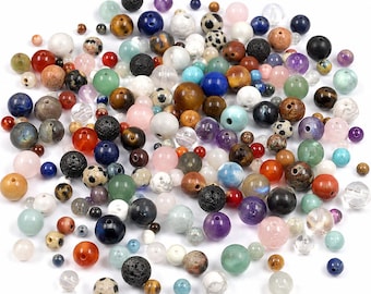 May include: A large collection of loose, spherical beads in various sizes, colors, and textures. The assortment includes smooth, polished, matte, and porous lava stone beads in shades of blue, green, brown, black, white, pink, and purple.