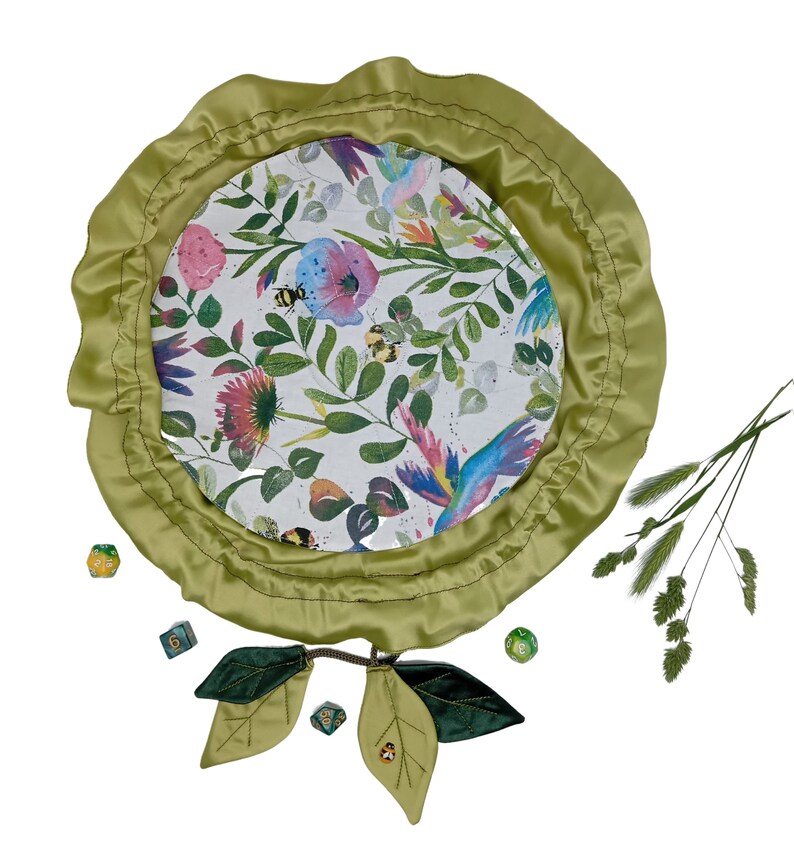 Puede incluir: Una bandeja de dados de fieltro verde con estampado floral y borde de sat&eacute;n verde. La bandeja est&aacute; rodeada de dados verdes y un par de hojas de fieltro verde.