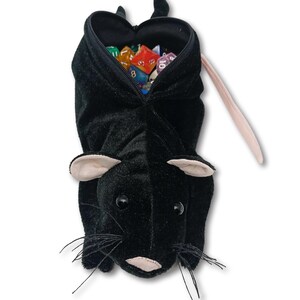 Pu&ograve; includere: Borsa da gioco in peluche nera a forma di topo con coda rosa e apertura con cerniera. La borsa &egrave; piena di dadi colorati.