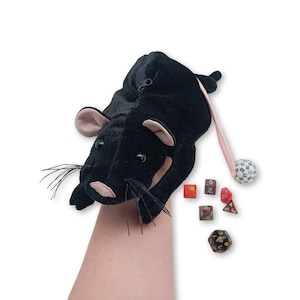 Pu&ograve; includere: Borsa da gioco in peluche nera a forma di topo con chiusura a zip e coda rosa. La borsa contiene una variet&agrave; di dadi, tra cui un d20, d12, d10, d8, d6 e un d4.