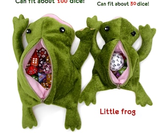 May include: Two plush green frog-shaped dice bags with pink lining and zippers. The larger frog is labeled "Big frog" and can fit about 100 dice. The smaller frog is labeled "Little frog" and can fit about 30 dice.