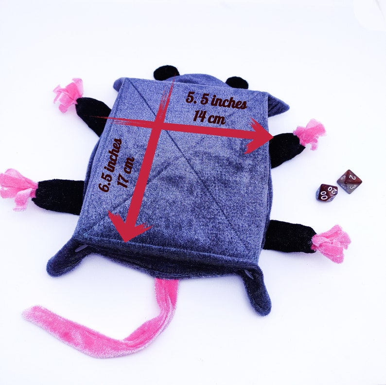 May include: A grey plush rat toy with pink and black accents. The toy is 17 cm tall and 14 cm wide. It has a long pink tail and two dice are lying next to it.
