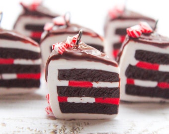 Puede incluir: Una colección de mini porciones de pastel de chocolate con detalles de bastones de caramelo rojo y blanco. Los pasteles están decorados con glaseado de chocolate y tienen un aspecto en capas.