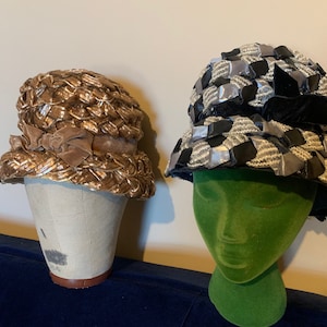 Puede incluir: Dos sombreros vintage en maniquíes. El sombrero de la izquierda es un sombrero de paja tejido con una cinta de terciopelo marrón. El sombrero de la derecha es un sombrero negro y plateado con un diseño tejido.
