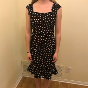 May include: A black and pink polka dot dress with a square neckline and a ruffled hem.