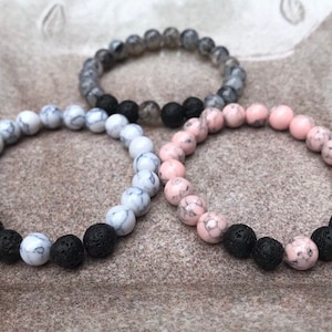 May include: Three bracelets made of black lava rock beads and white and pink marbled beads.
