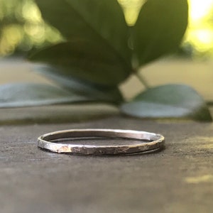 May include: A thin silver band ring with a hammered texture.