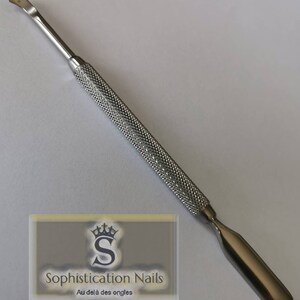 Peut inclure: Un pousse-cuticules en métal argenté avec une poignée texturée et une extrémité arrondie. L'outil est utilisé pour repousser les cuticules et nettoyer le vernis à ongles.