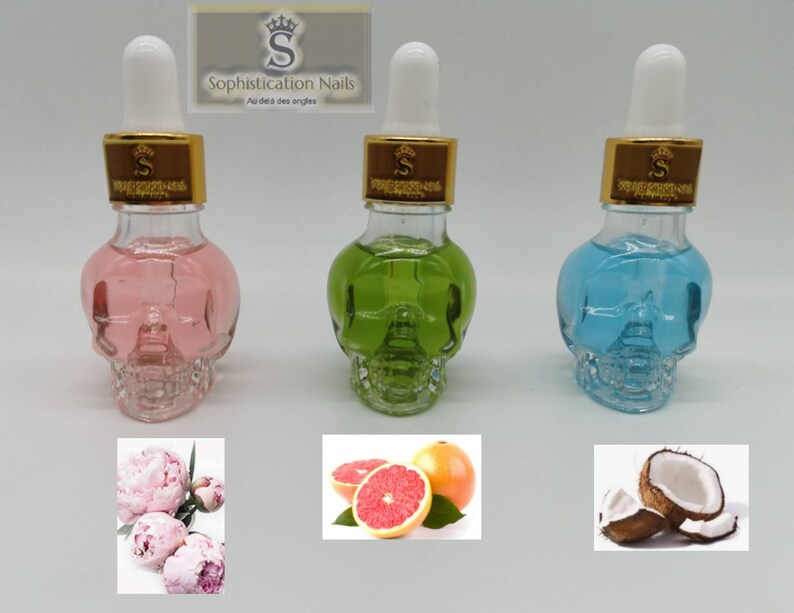 May include: Three glass bottles shaped like skulls filled with colored liquids. The bottles have gold lids and droppers. The bottles are arranged in a row from left to right: pink, green, and blue. Below each bottle is a picture of a flower, fruit, or coconut.