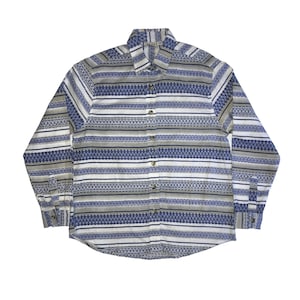 Puede incluir: Una camisa de manga larga con botones, fondo blanco y rayas horizontales azules y marrones. Las rayas tienen un patrón geométrico.