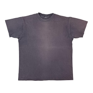 Op de afbeelding: Een vervaagd houtskoolgrijs t-shirt met een ronde hals en korte mouwen. Het shirt heeft een vintage, versleten uitstraling, met subtiele kleurvariaties over de stof. De algehele stijl is casual en relaxed.