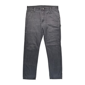 Peut inclure: Un pantalon de travail en jean gris. Le pantalon a une conception classique &agrave; cinq poches, avec des poches suppl&eacute;mentaires et des coutures renforc&eacute;es. Il est fait d'un mat&eacute;riau en jean durable et comporte une fermeture &agrave; bouton et &agrave; glissi&egrave;re.