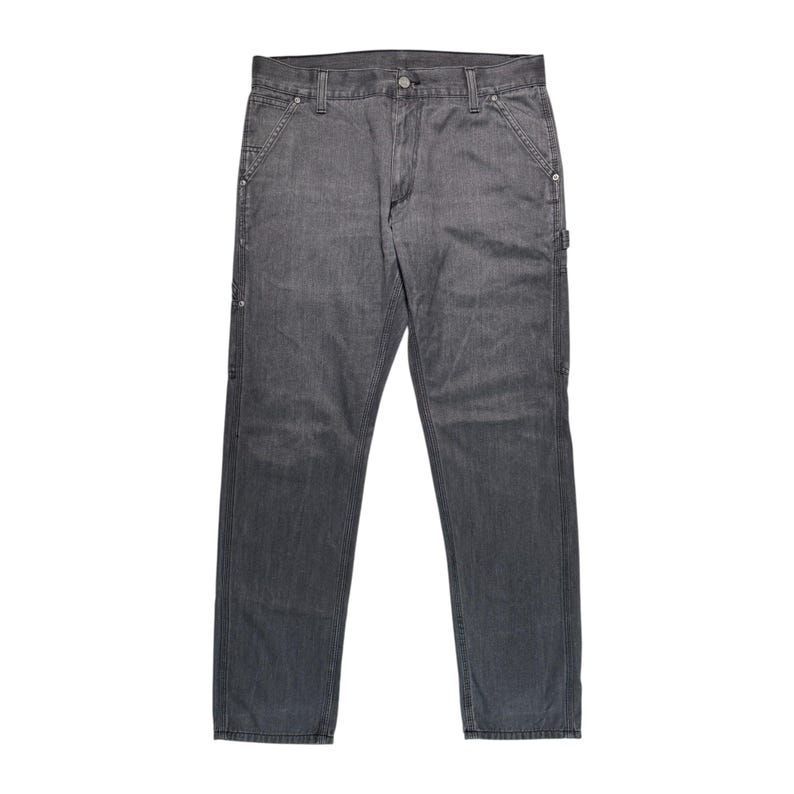 Peut inclure: Un pantalon de travail en jean gris. Le pantalon a une conception classique &agrave; cinq poches, avec des poches suppl&eacute;mentaires et des coutures renforc&eacute;es. Il est fait d'un mat&eacute;riau en jean durable et comporte une fermeture &agrave; bouton et &agrave; glissi&egrave;re.