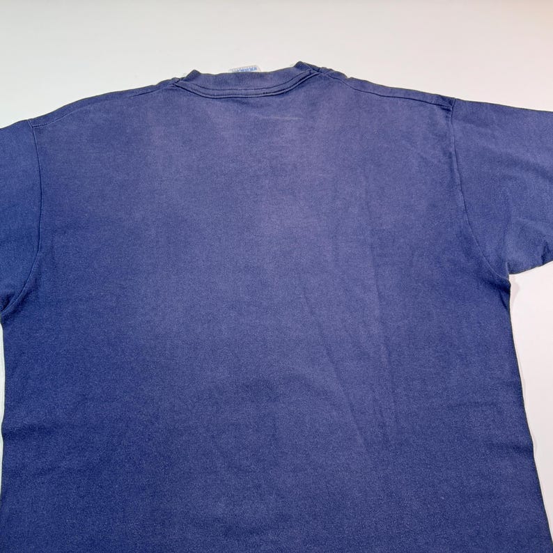 May include: A plain, dark blue t-shirt with a faded look. The shirt is made of a soft, comfortable material.