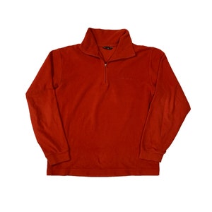 Puede incluir: Un jersey rojo de manga larga con cremallera y el texto "ONE IDA" en la parte delantera.