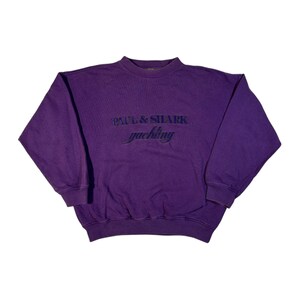 May include: Purple sweatshirt with a black embroidered logo that says "Paul & Shark yachting".