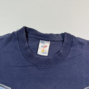 May include: A navy blue t-shirt with a white tag that says "Sport-Biz" and a red, white, and blue logo.