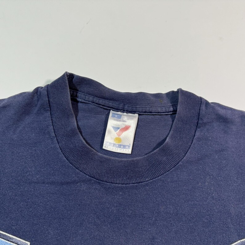 May include: A navy blue t-shirt with a white tag that says "Sport-Biz" and a red, white, and blue logo.