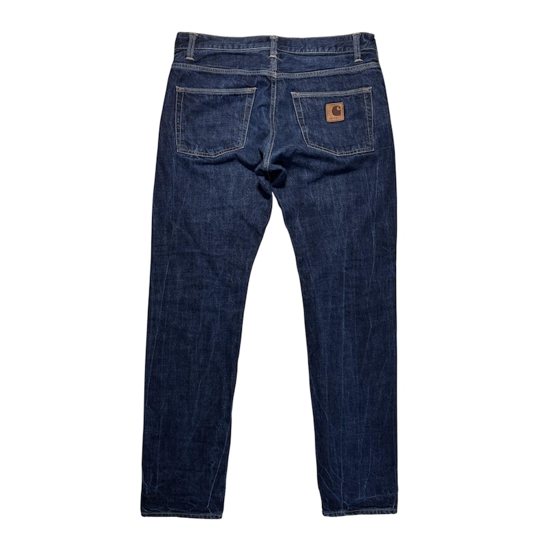 Puede incluir: Vaqueros de mezclilla azul oscuro con un dise&ntilde;o cl&aacute;sico de cinco bolsillos. Los vaqueros tienen un corte de pierna recta y un parche de cuero marr&oacute;n en el bolsillo trasero. Los vaqueros est&aacute;n hechos de un material de mezclilla duradero.