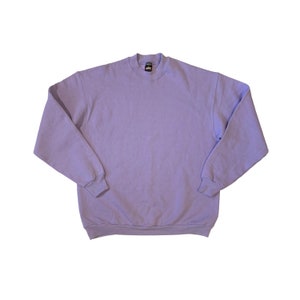Pode incluir: Uma camisa de gola redonda de cor lavanda.