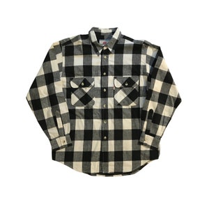 Puede incluir: Una camisa abotonada a cuadros blancos y negros. La camisa tiene dos bolsillos en el pecho con cierres de botón y puños abotonados. El cuello es abotonado. La camisa está hecha de una tela suave y tejida.