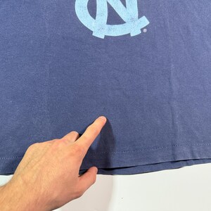 May include: A navy blue t-shirt with a light blue University of North Carolina Tar Heels logo.