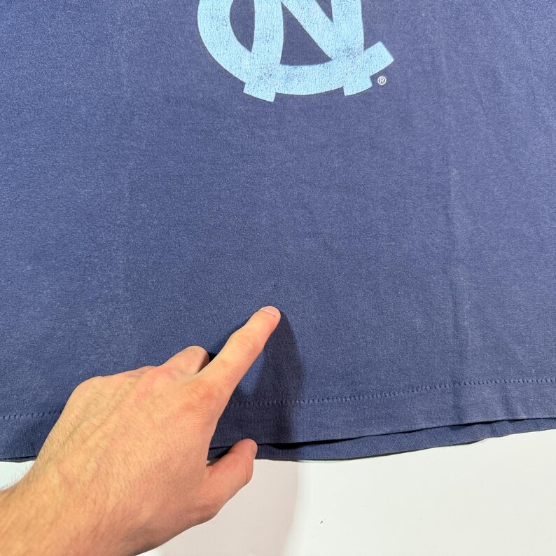 May include: A navy blue t-shirt with a light blue University of North Carolina Tar Heels logo.