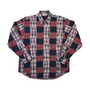 May include: A long-sleeved patchwork shirt with a mix of red, navy, and white plaid patterns. The shirt has a button-down front, a collar, and buttoned cuffs. The design incorporates various plaid squares.