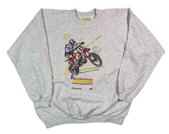 May include: Pale grey sweatshirt featuring a motocross racer on a red and white motorbike. The graphic includes the text "7th International Supercross Indoor" and the Honda and Elf logos. The sweatshirt has long sleeves and a crew neck.