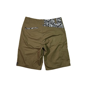 May include: Khaki-colored shorts with a black and white patterned design on the back pockets and waistband. The shorts have a cargo pocket on the right side and a small logo near the hem. The shorts are made of a durable material.