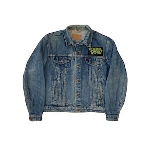 May include: A blue denim jacket with a black patch that says "Municipal Waste" in green lettering.