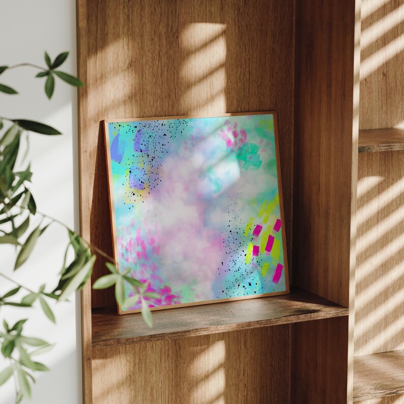 May include: Abstract art print with a colorful, watercolor-like background and bright pink, yellow, and blue accents. The print is framed in a wooden frame.