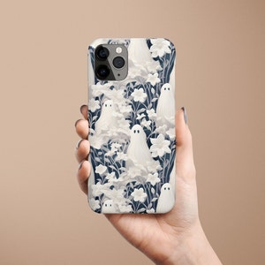 May include: A white iPhone case with a pattern of white ghosts and flowers on a dark blue background.