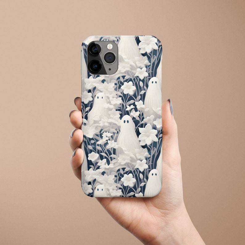 May include: A white iPhone case with a pattern of white ghosts and flowers on a dark blue background.