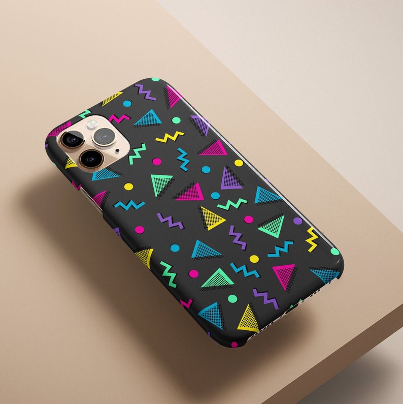 May include: Black smartphone case with a vibrant 80s-inspired geometric pattern. The design features colorful triangles, zigzags, and dots in shades of pink, yellow, blue, and purple. The case is designed to fit a smartphone.